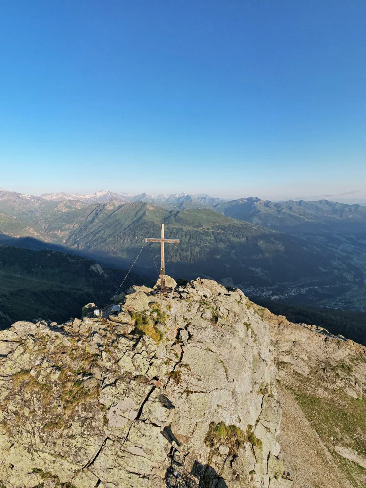 Gipfelkreuz auf sonnigem Berggrat mit Blick ins Gasteinertal – Symbol für alpine Freiheit beim Wandern mit Hund