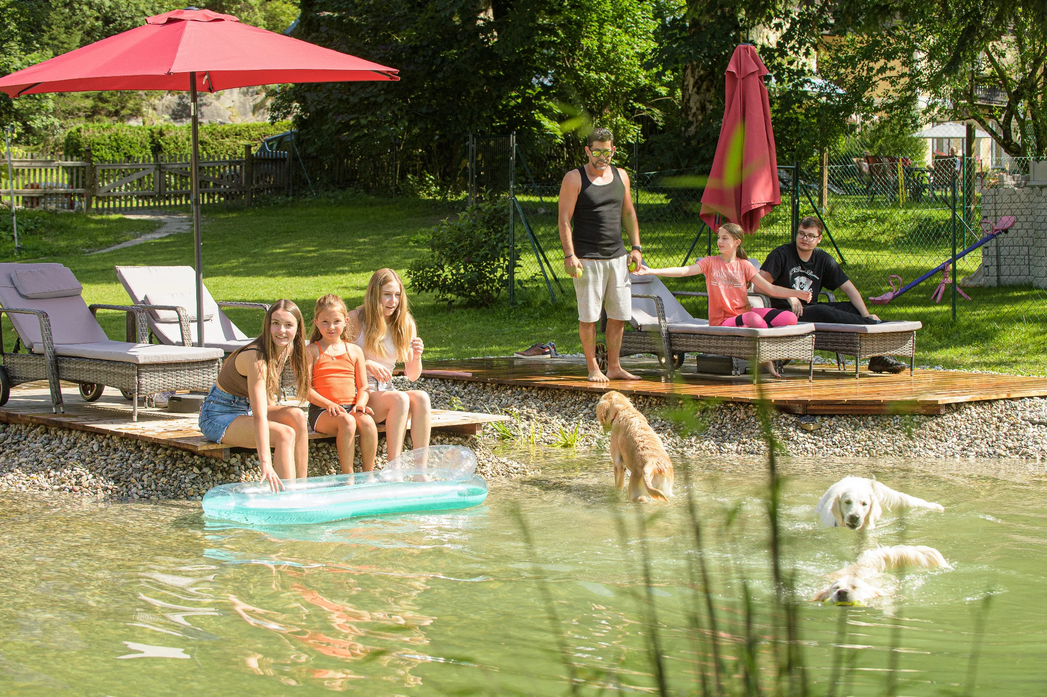 Sommerurlaub mit Hund in Gastein – Familie mit Hunden am Badeteich unter der Sonne