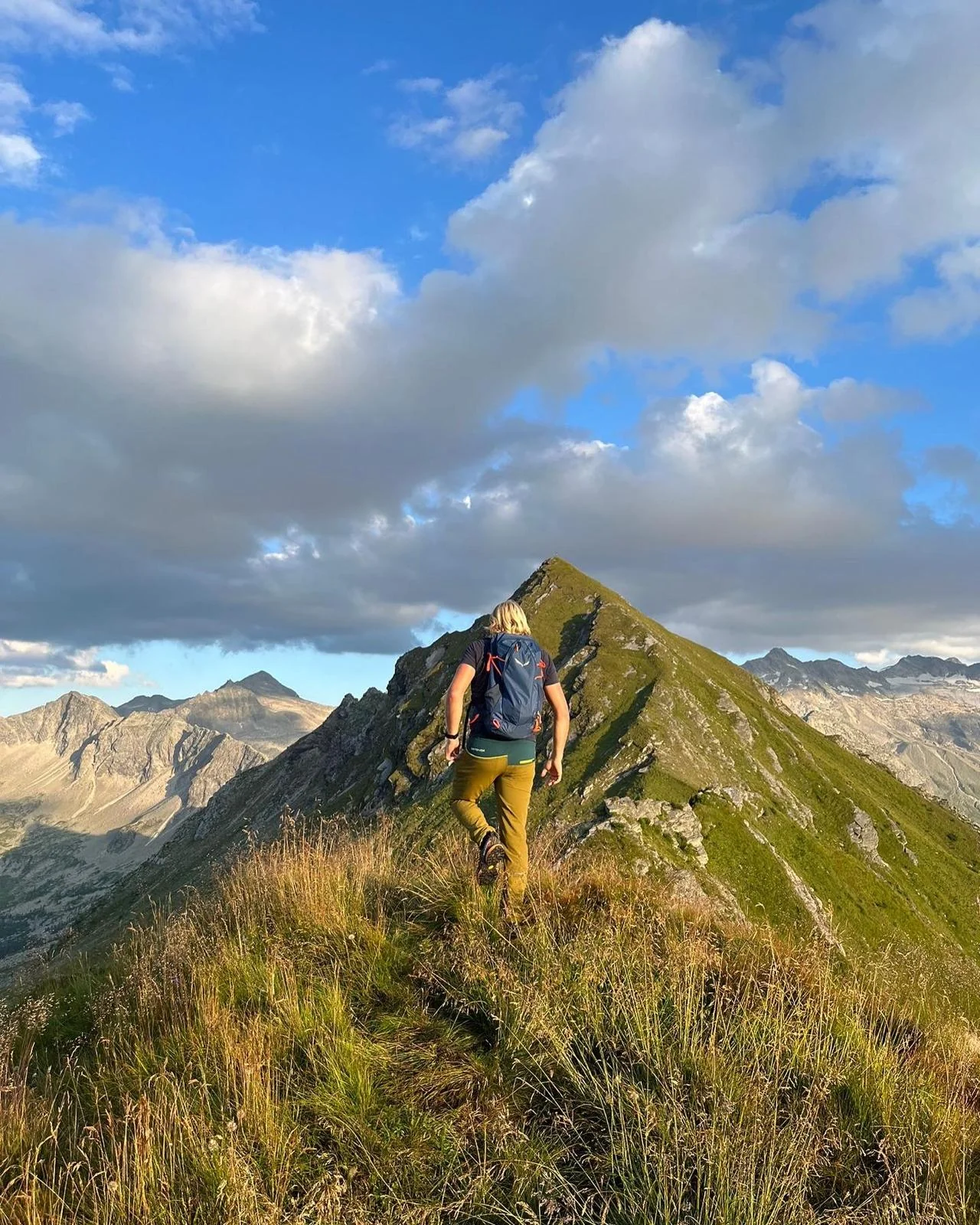 Sommerurlaub mit Hund in Gastein – Wanderer auf einem Grat mit Blick auf die Berge bei Abendsonne